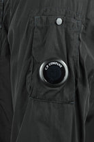 Black overshirt with circular logo button and flap pocket on chest