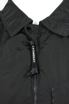 Black overshirt collar close-up with zipper and C.P. Company logo tab
