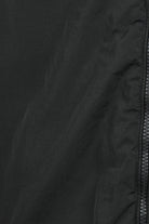 Black fabric close-up showing front zipper track on overshirt