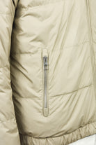 Beige quilted jacket close-up of full-zip slider and stitched panels