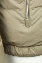 Beige quilted jacket close-up of hem seam and zipper guard panel