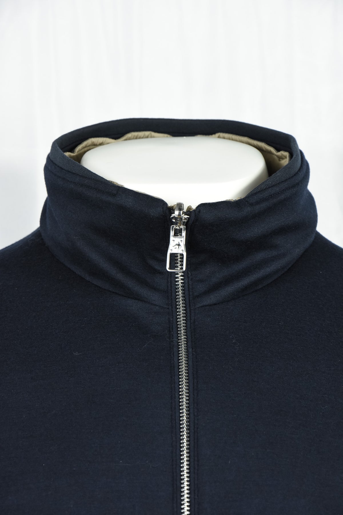 Dark blue jacket collar close-up with full-zip slider and interior beige lining