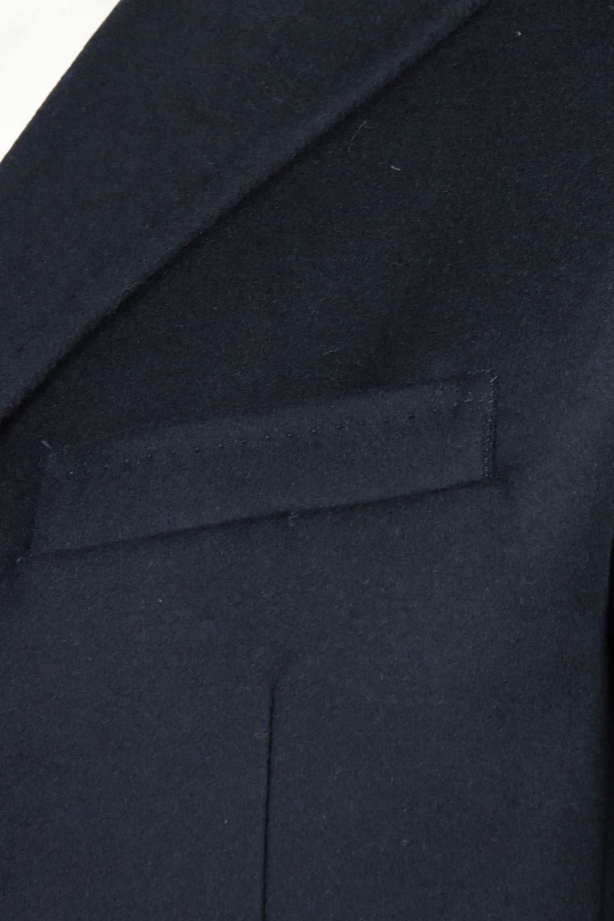 Dark wool and cashmere overcoat detail showing chest welt pocket and lapel edge