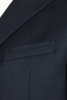 Dark wool and cashmere overcoat detail showing chest welt pocket and lapel edge