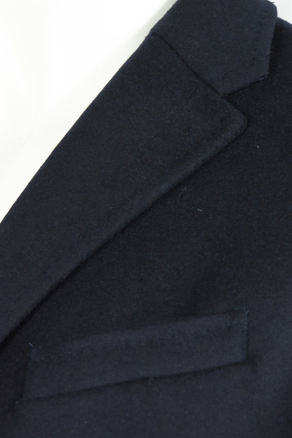 Overcoat detail of notched lapel and chest welt pocket in dark wool-cashmere fabric
