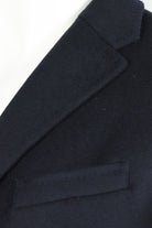 Overcoat detail of notched lapel and chest welt pocket in dark wool-cashmere fabric