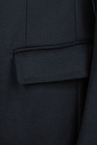 Dark wool and cashmere overcoat detail showing a flap pocket and vertical seam