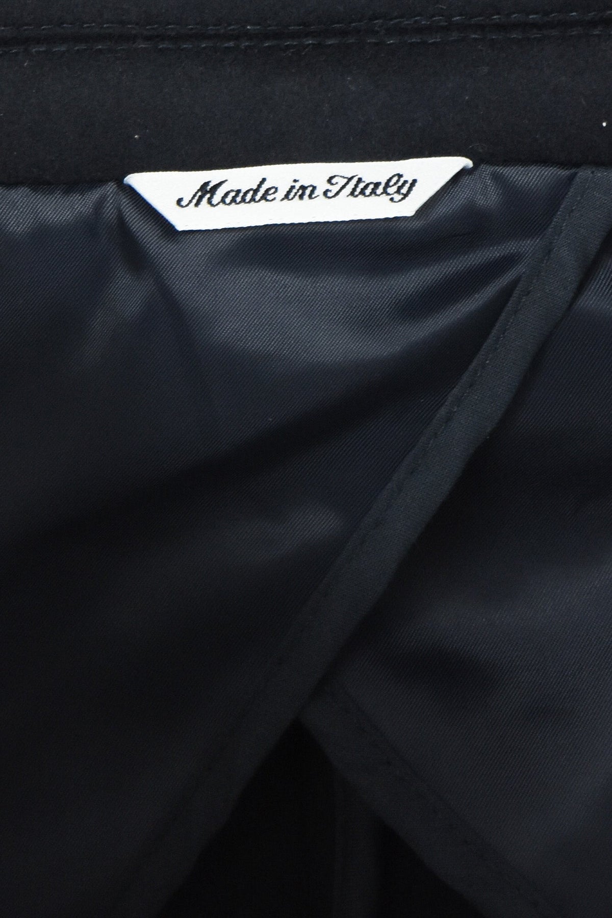 Overcoat interior label reading Made in Italy beside dark lining