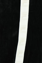 White side tape stripe with repeating Fila lettering on black velour pants