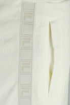 White velour track pants with vertical FILA tape stripe and side opening