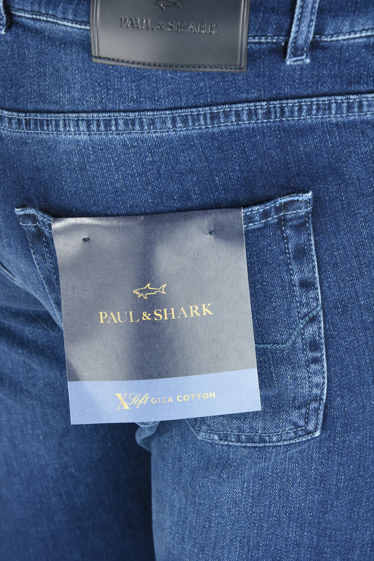 Close-up of mid-blue jeans with a Giza cotton label beside the back pocket