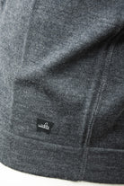 Close-up of the cardigan's merino knit, hem stitching, and WAHTS logo tab