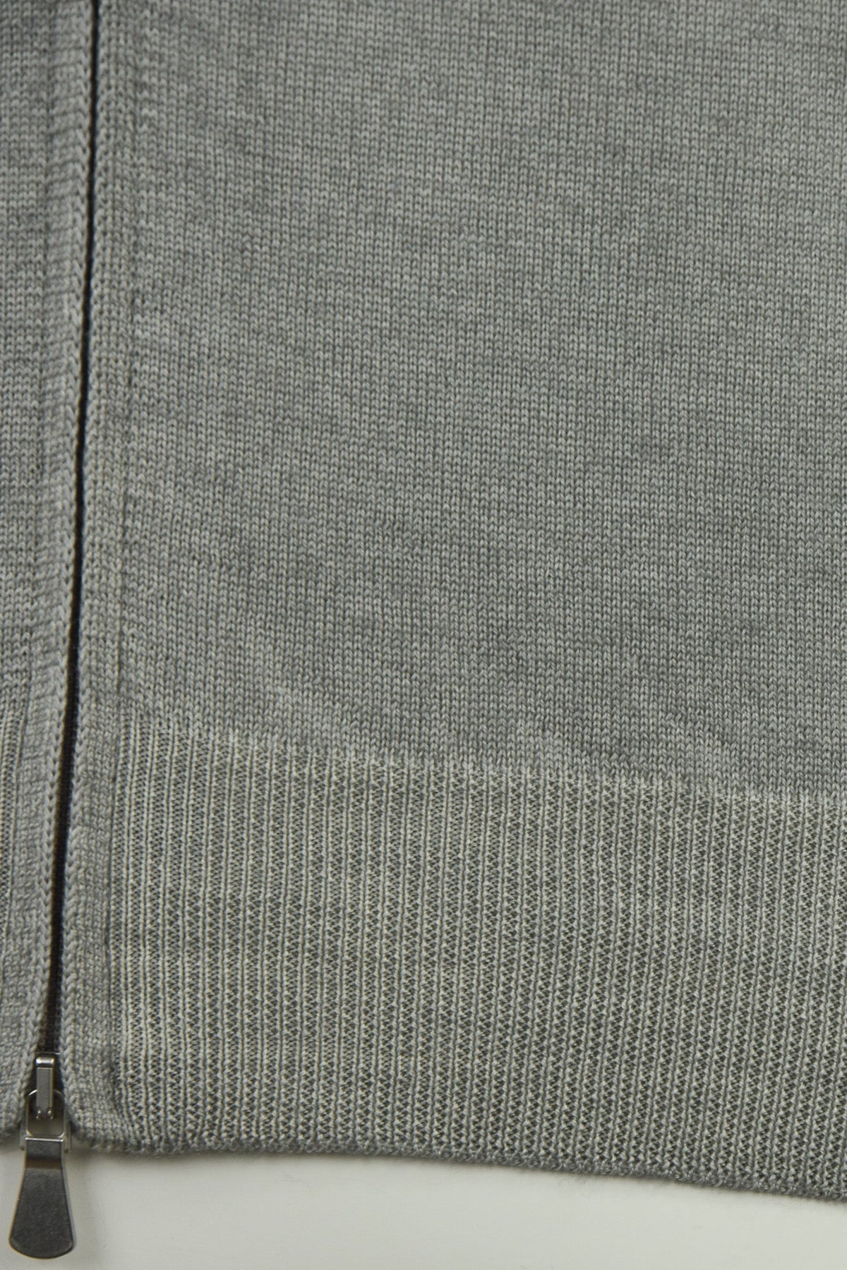 Cardigan close-up showing the ribbed hem and zipper base