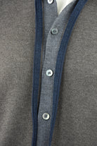 Knitted cardigan close-up showing blue zipper trim and buttoned front placket