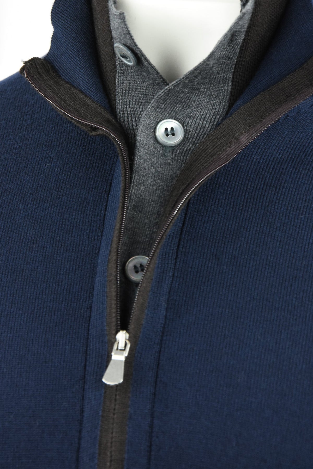 Navy cardigan front detail with a zip opening over a gray buttoned layer