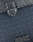 Blue flap detail with square leather patch, stitching, and textured tech-weave fabric.