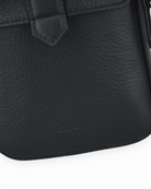 Black leather crossbody bag close-up with Canali logo stamp on front panel