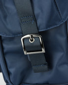 Adjustable nylon strap with metal D-ring buckle on blue backpack panel.