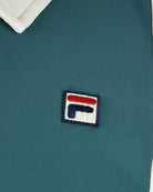 Fila track jacket logo patch on teal textured fabric.
