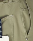 Beige pant pocket and seam details with snap closure and hangtag edge