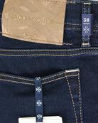 Dark wash denim with size 38 waist label, pocket stitching, and brand tag