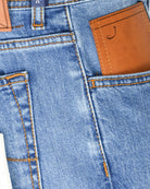 Men's blue stretch denim jeans detail: brown leather patch on pocket, orange seam