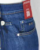 Dark blue denim jeans front pocket with metal button, RF patch, and yellow contrast stitch