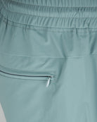 Teal blue shorts close-up: elastic waistband and pocket opening with trim.
