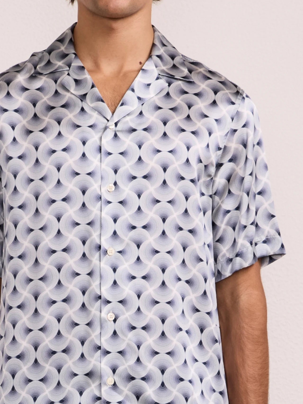 Front view of short sleeve shirt with spiral print, camp collar, and button placket