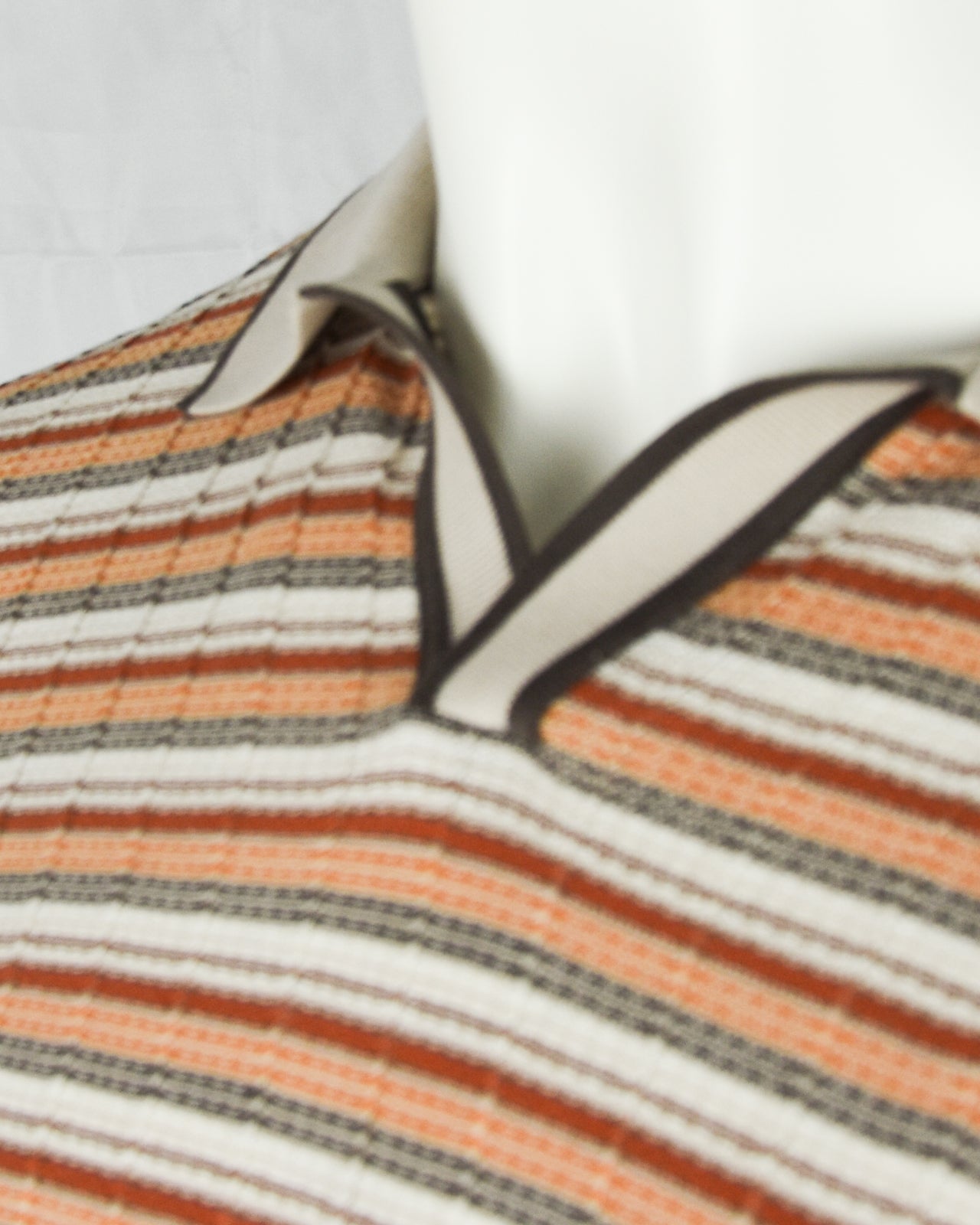 Open-collar polo collar with ribbed trim; cream, orange, and gray striped knit.