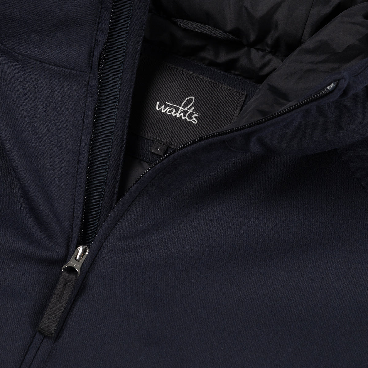 Deep navy jacket close-up: front zipper, hood lining, and WAHTS logo label