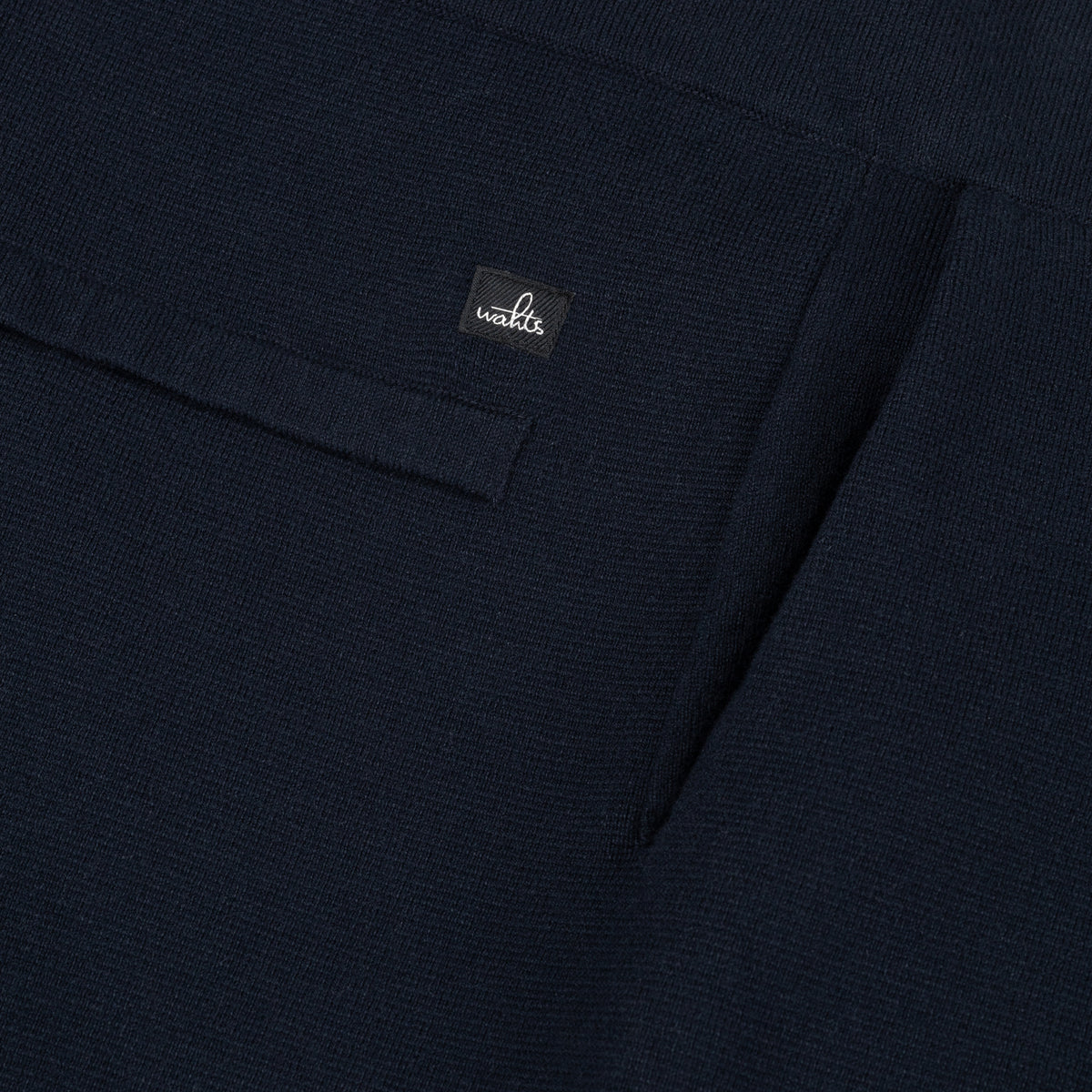 Dark knit lounge pants fabric close-up with waistband label and stitched seam