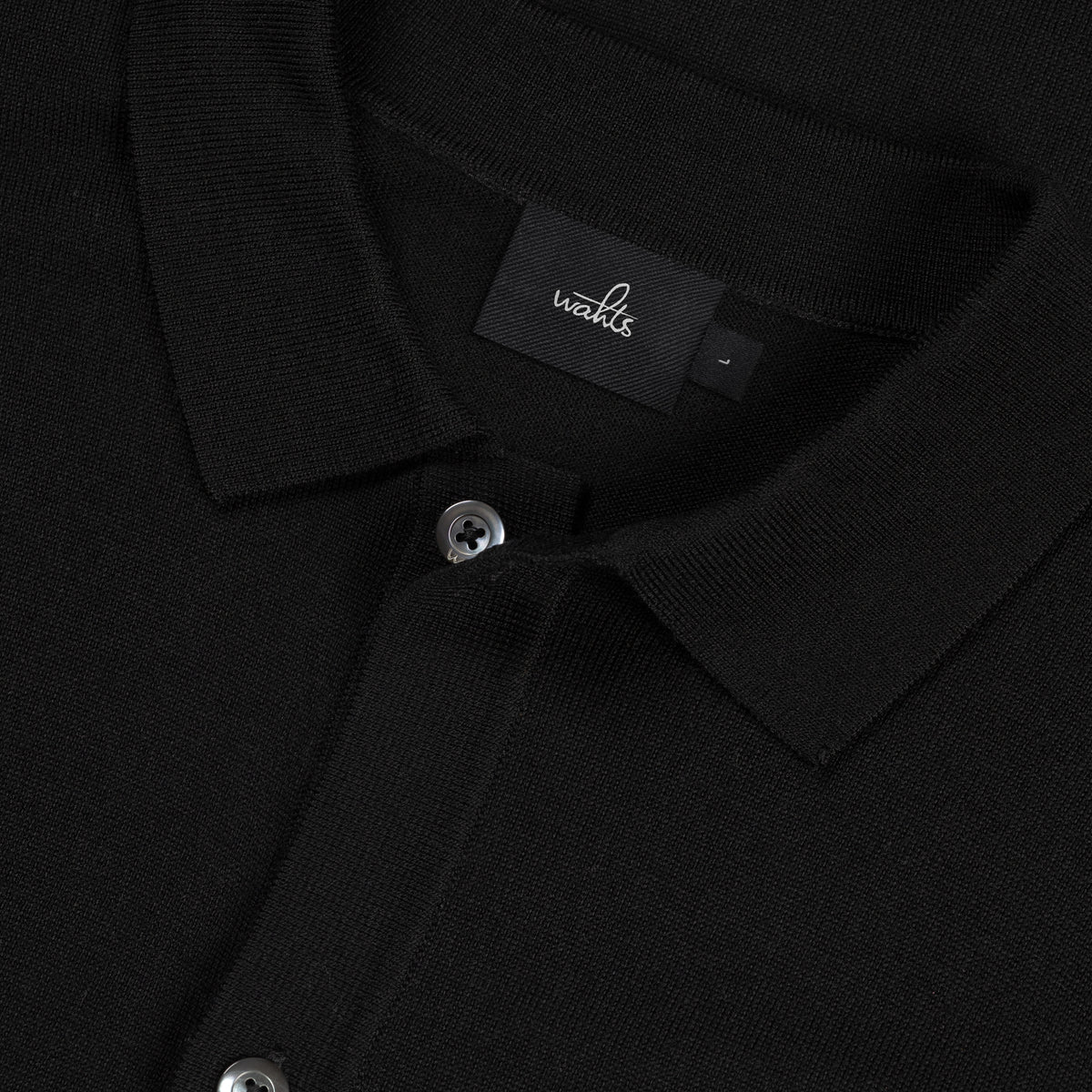 Black merino cardigan close-up of logo label and metal button