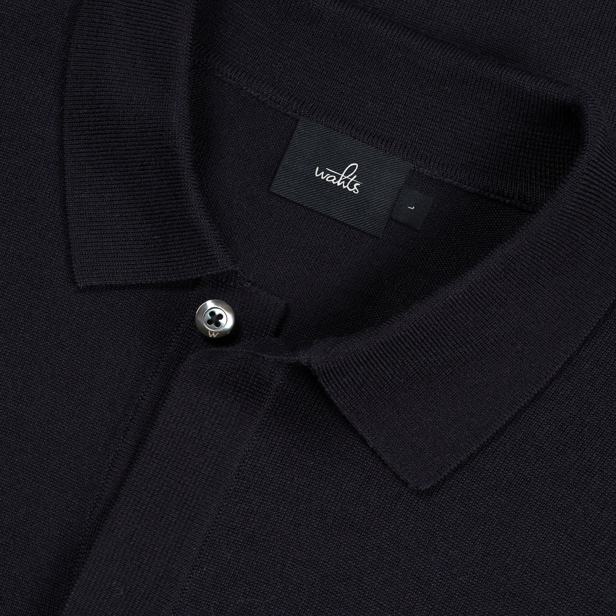 Close-up of dark blue merino cardigan collar, button front, and WAH... label