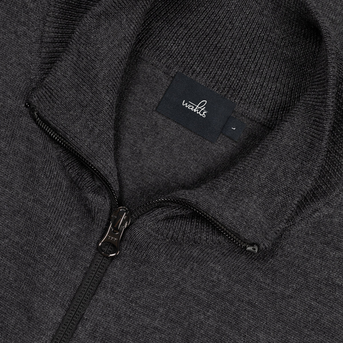 Merino cardigan close-up: WAHTS label, metal zipper, textured knit in dark melange