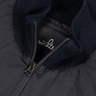 Close-up of WAHTS tag and metal zipper on ribbed knit collar of hybrid jacket.