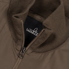 Close-up of wahts logo zipper on dark olive jacket with ribbed knit collar