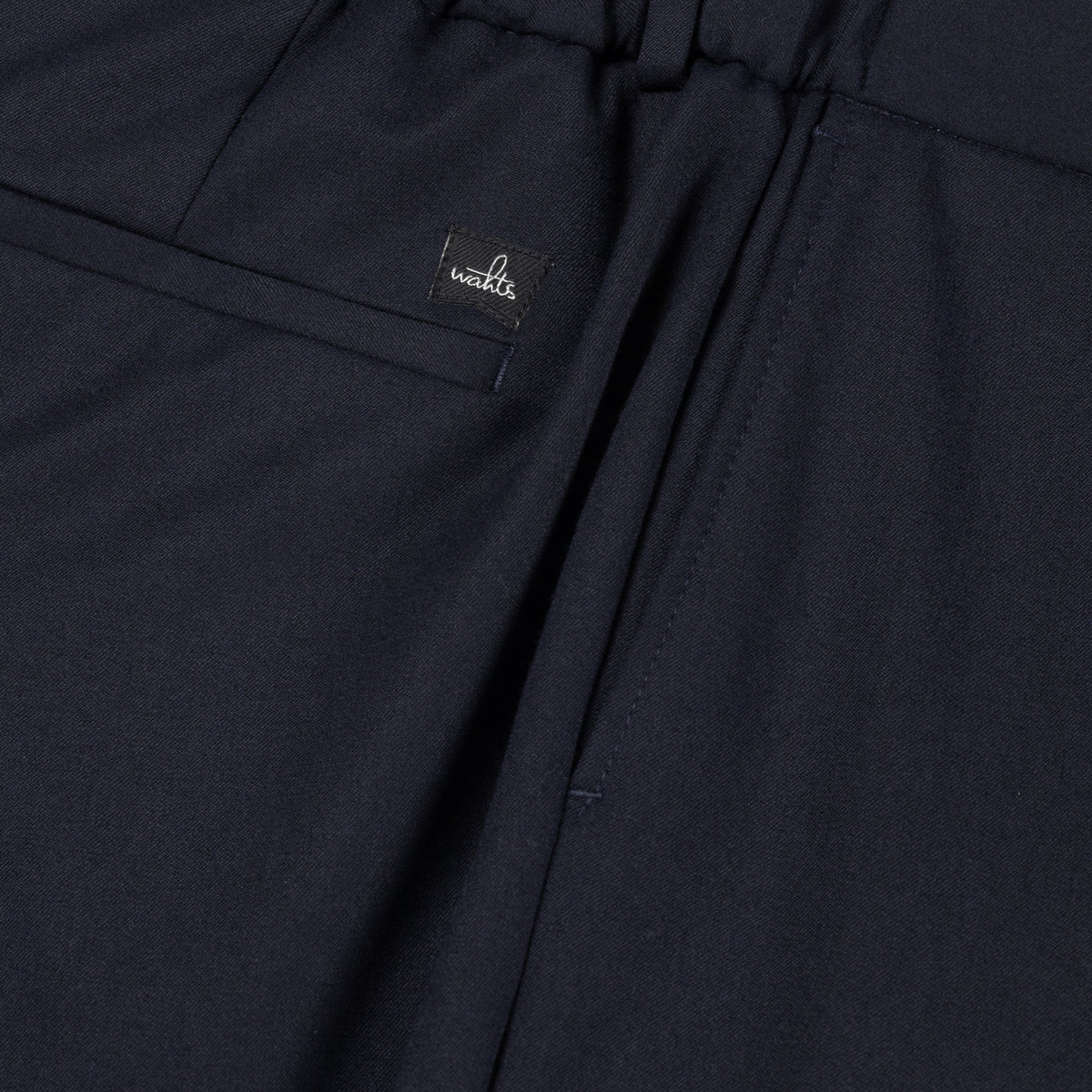 Deep navy soft wool trouser detail with stitched logo patch