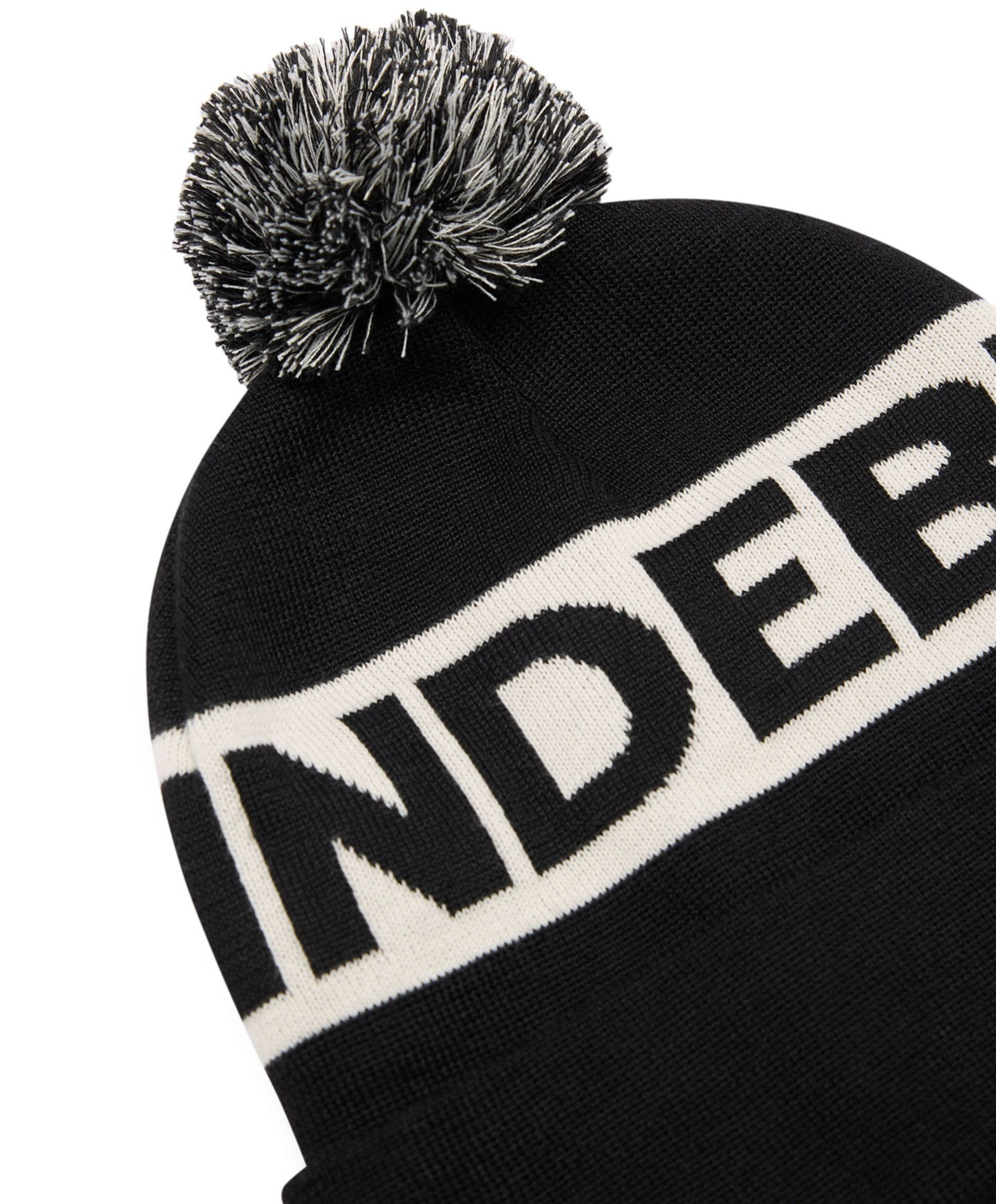 Black knit beanie close-up with pom-pom and white logo band lettering