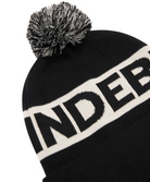 Black knit beanie close-up with pom-pom and white logo band lettering