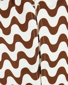 Swim shorts fly and seam close-up, brown-and-ecru wavy fabric, stitched edges