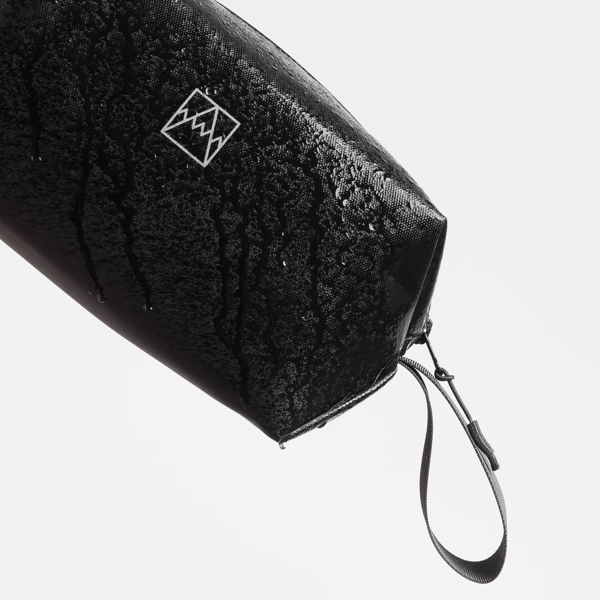 Waterproof wash bag in dark fabric with white logo mark and attached wrist strap