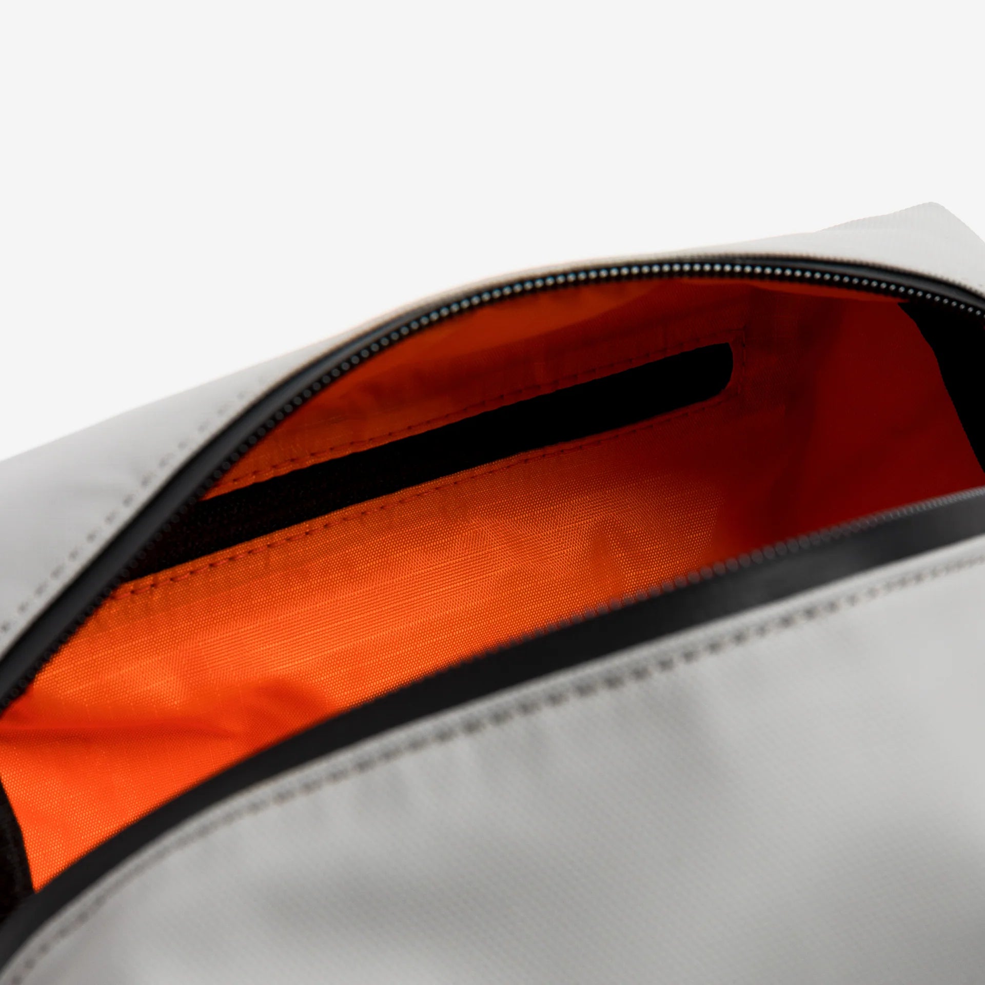 Waterproof wash bag showing orange inner lining with zippered top and dark trim