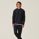 Deep navy crewneck sweater with ribbed cuffs and hem, worn with dark pants