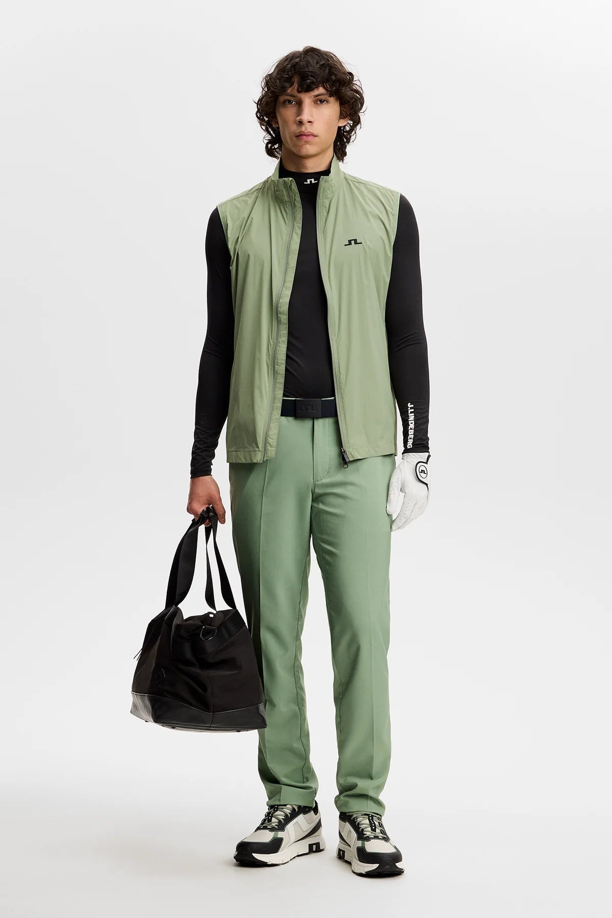 Black underlayer compression top with mock neck, styled under green outerwear.