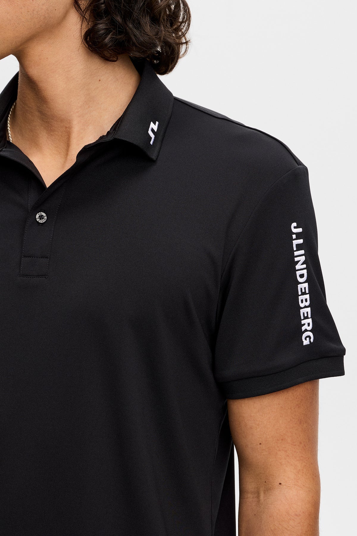 Black polo shirt with button collar and vertical logo on sleeve
