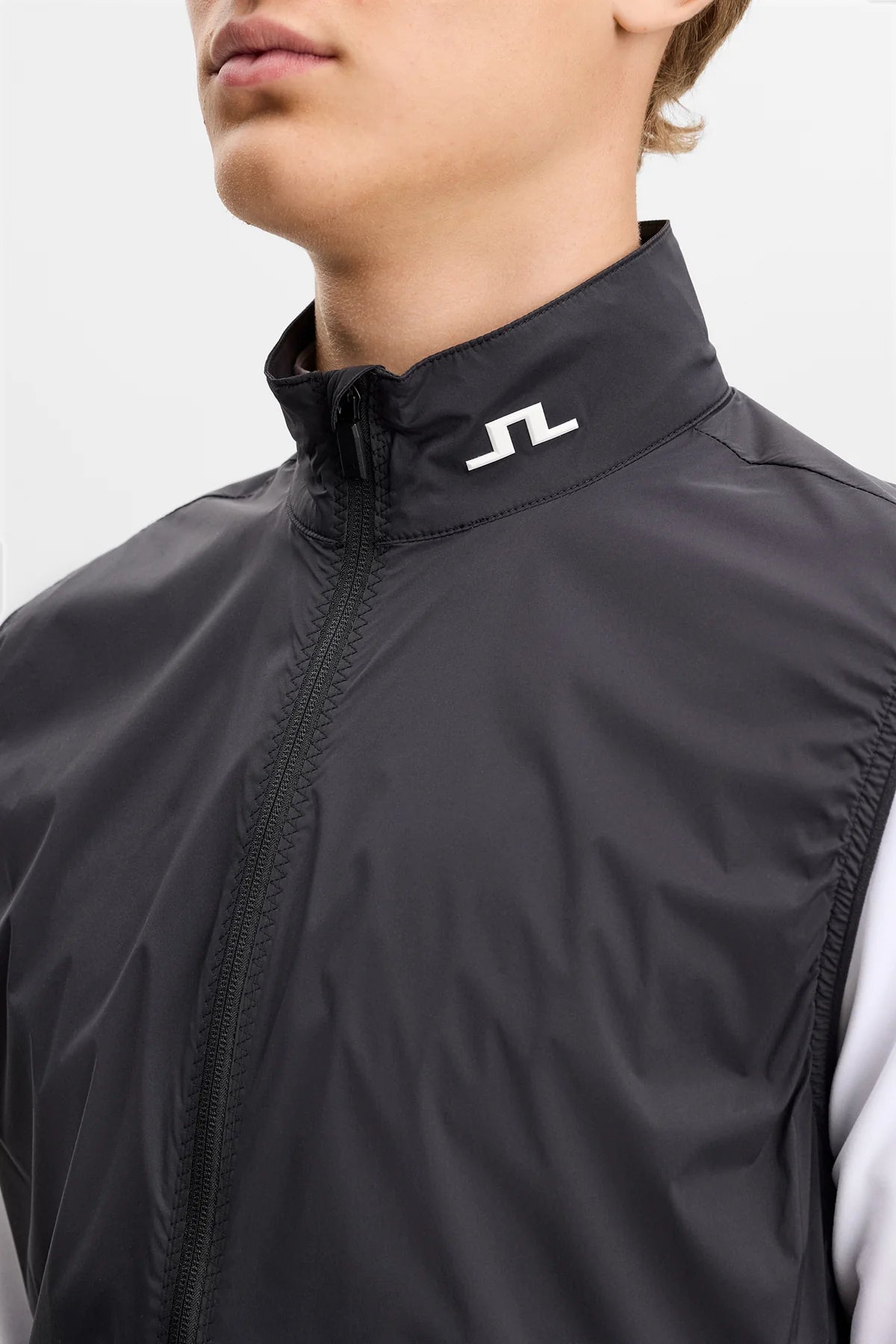 Black packable vest close-up of stand collar and zipper with J.Lindeberg logo.