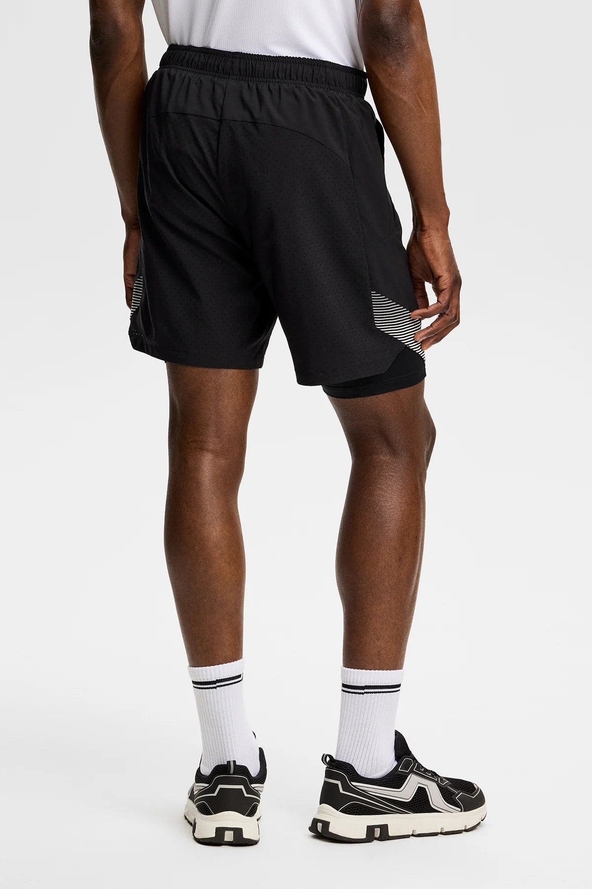 Black shorts with elastic waistband and diagonal striped side insert, back view