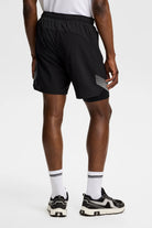 Black shorts with elastic waistband and diagonal striped side insert, back view