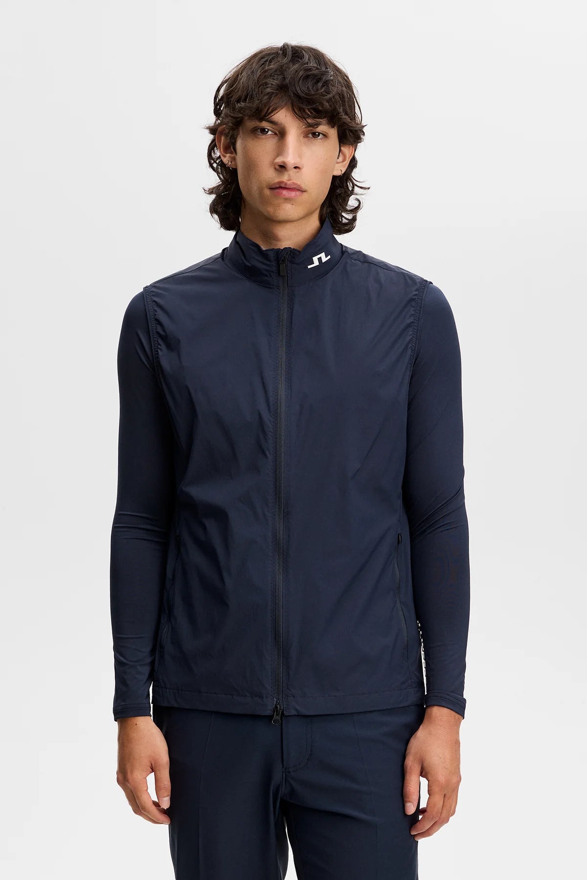 Navy full-zip vest with stand collar, model wearing over long-sleeve top